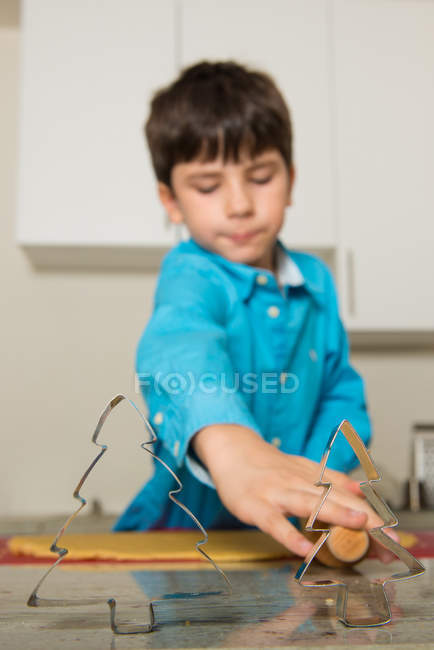 Boy using cookie cutters in kitchen — Stock Photo