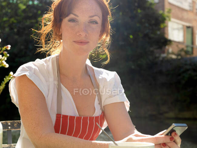 Woman in apron using cell phone — Stock Photo