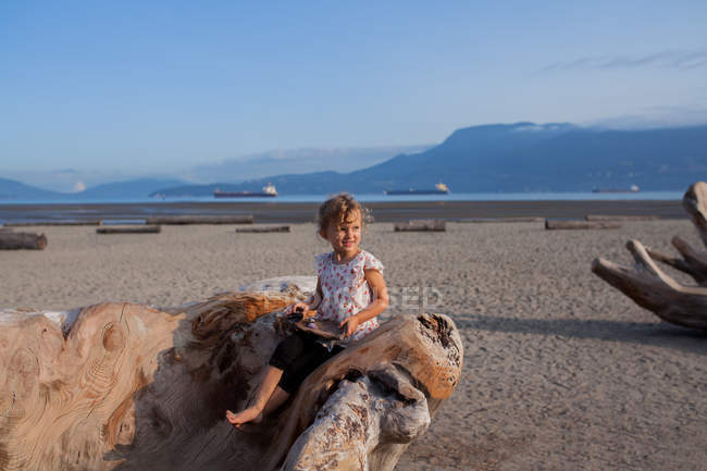 Little girl playing on wood sculpture on beach, Vancouver, British Columbia, Canada — Stock Photo