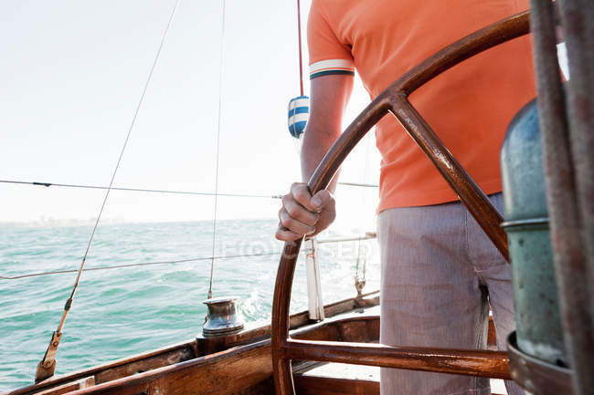Young man steering yacht — Stock Photo