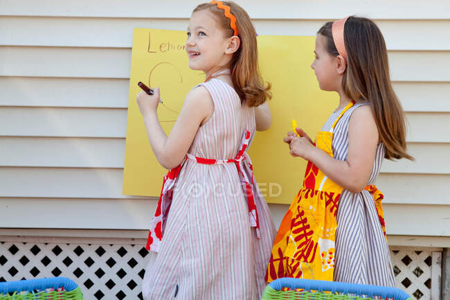 Дівчата роблять знак за продаж саморобного лимонаду. — стокове фото