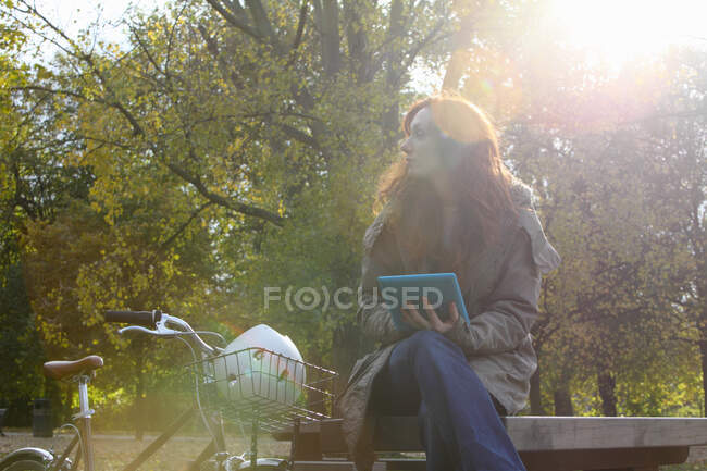 Женщина сидит с велосипедом в парке — стоковое фото