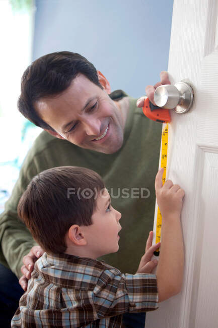 Pai e filho medindo porta em casa — Fotografia de Stock