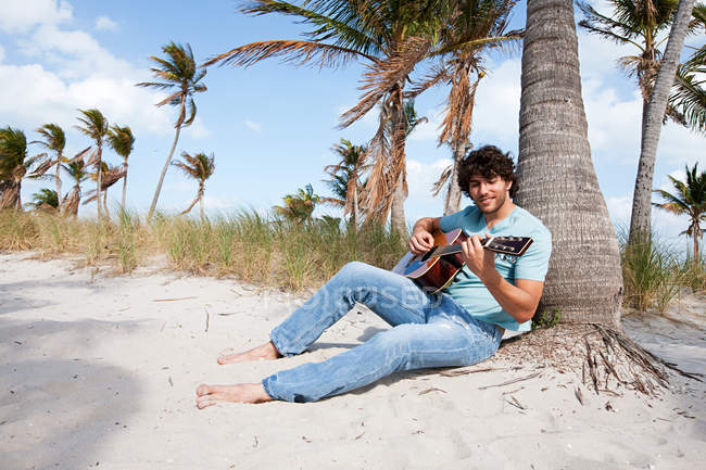 Молодий чоловік грає на гітарі на пляжі, портрет — стокове фото