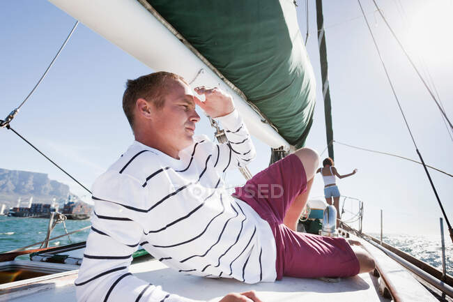 Young man on yacht, shielding eyes — Stock Photo