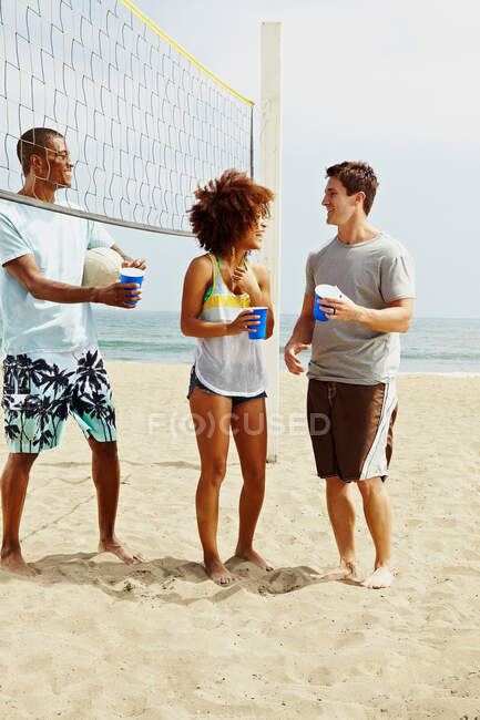 Friends on beach with volleyball and net — Stock Photo