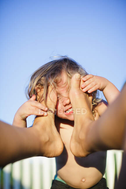 Чоловічий малюк з обличчям проти маминих голих ніг — стокове фото
