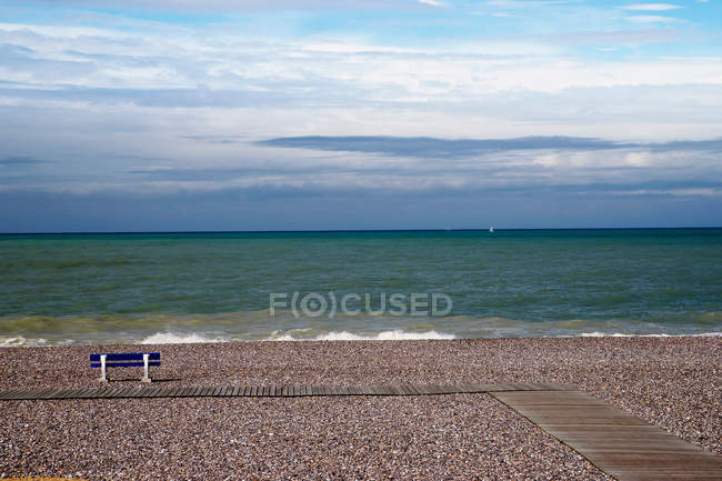 Panchina vuota sulla spiaggia di ghiaia — Foto stock