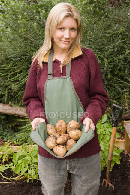 Усміхнена жінка тримає картоплю — стокове фото