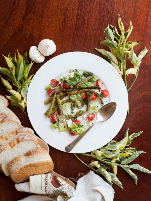 Тарілка салату зі свіжим нарізаним хлібом, поданим на столі — стокове фото