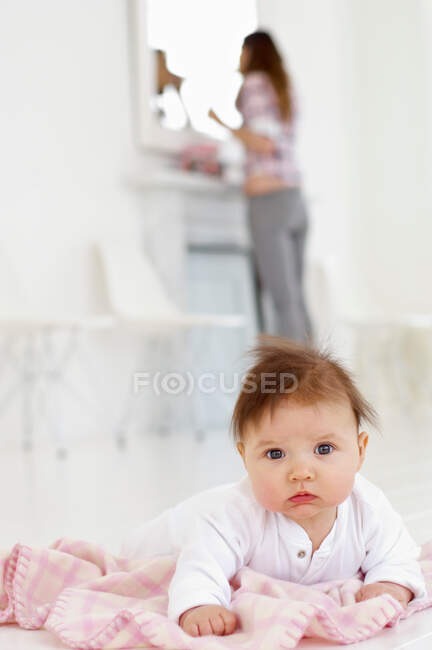 Bébé fille avec mère en arrière-plan — Photo de stock