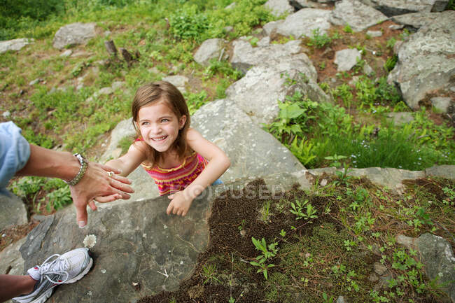 Mother helping daughter climb rocks — Stock Photo