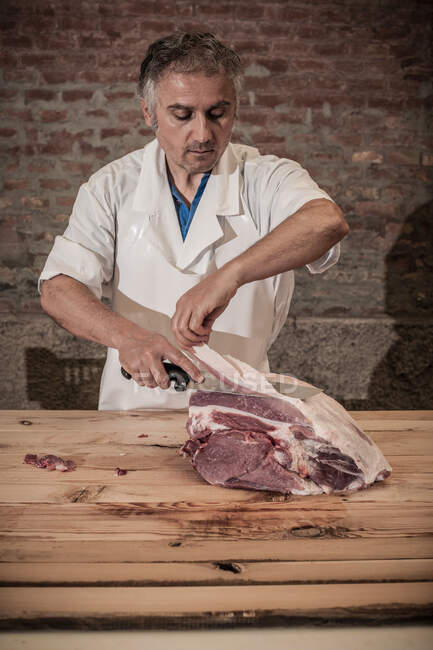 Мясник режет мясо в магазине — стоковое фото