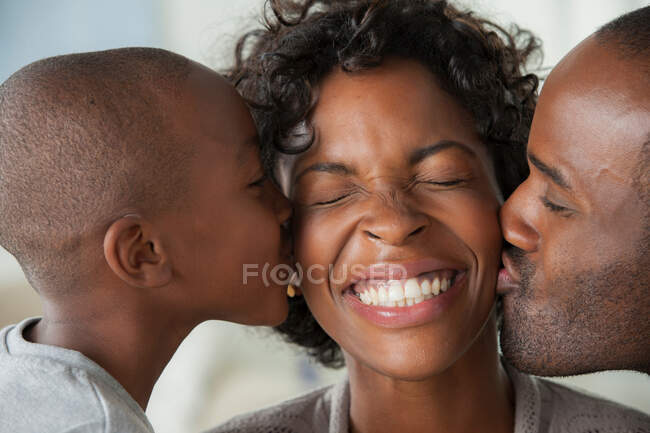 Хлопчик і чоловік цілують жінку на щоках — стокове фото