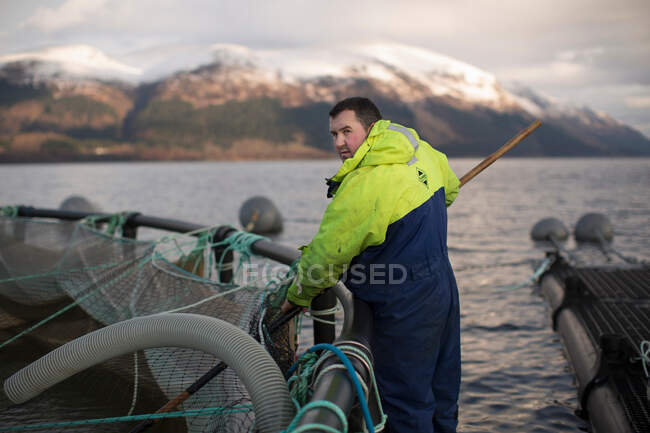 Lavoratore presso l'allevamento di salmoni nel lago rurale — Foto stock