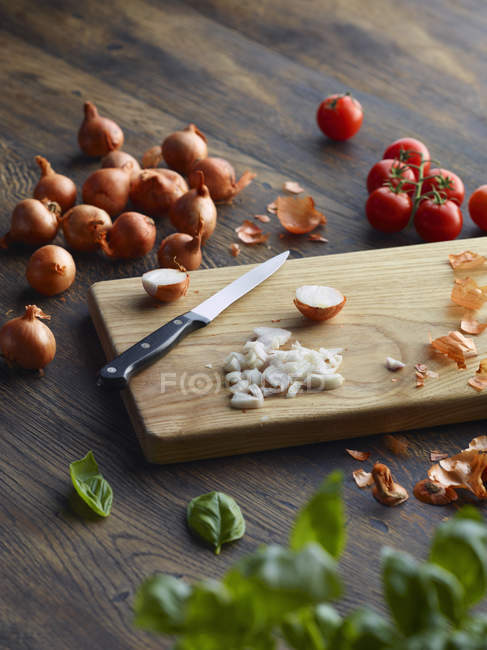 Tomates frescos de albahaca y cereza con cebolla picada en la tabla de cortar - foto de stock