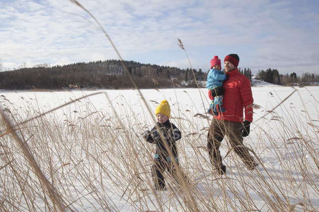 Отец гуляет с двумя сыновьями в заснеженном пейзаже — стоковое фото