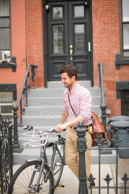 Homme poussant vélo hors de la porte d'entrée — Photo de stock