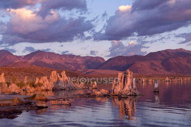 Scenic view of cloudy sunset sky above lake with rock formations — Stock Photo