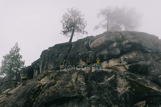 Two young men standing on mountainside, photographing view, near Shaver Lake, California, USA — Stock Photo