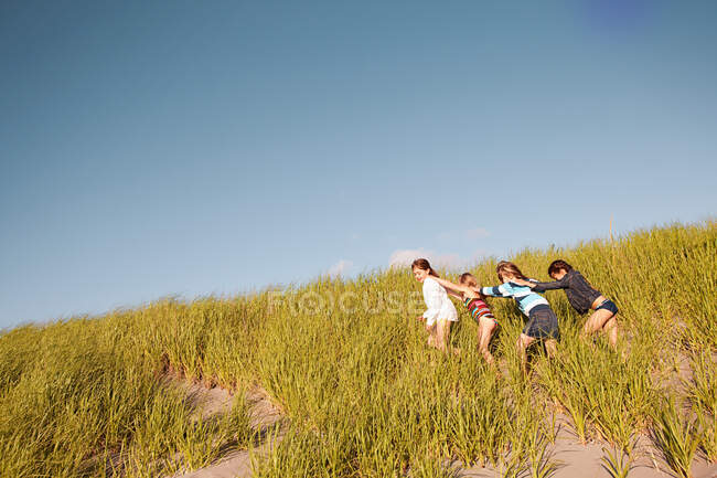 Meninas caminhando através de grama longa na praia — Fotografia de Stock