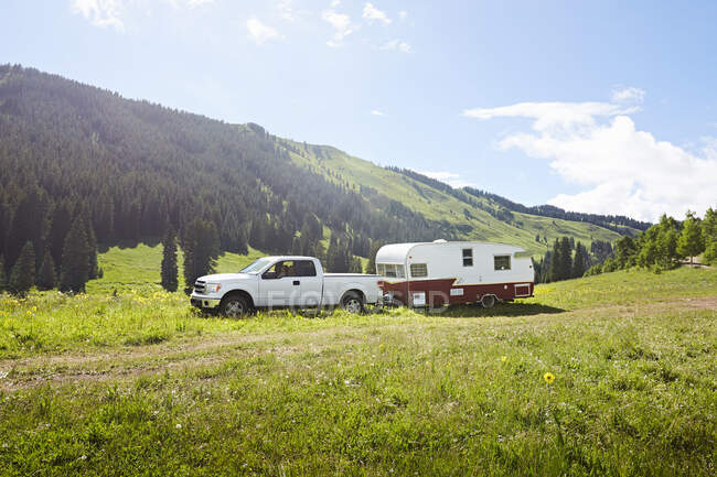 Un camion e camper trailer allestito in un campo di fiori selvatici vicino a Crested Butte, Colordao. — Foto stock