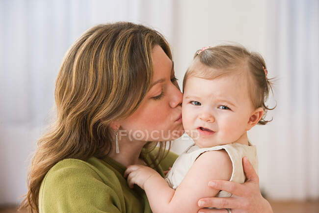 Madre besar bebé niña - foto de stock