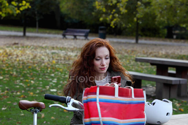 Frau sitzt mit Fahrrad im Park — Stockfoto