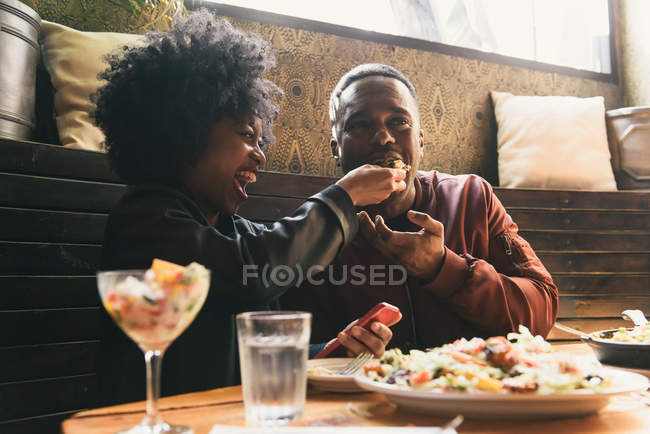 Pareja compartiendo comida juntos en la cafetería - foto de stock