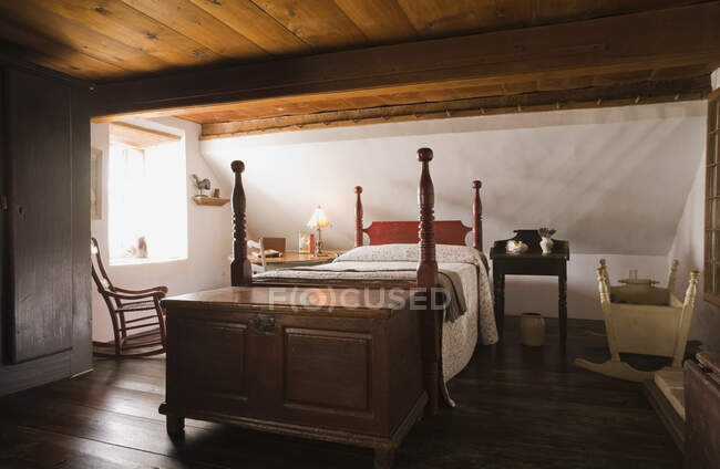 Lit double et vieux coffre de rangement en bois dans la chambre principale à l'étage supérieur à l'intérieur d'une ancienne maison de style cottage en pierre des champs (1785), Québec, Canada. Cette image est une propriété libérée. CUPR0260 — Photo de stock