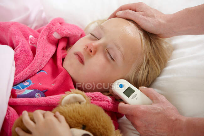 Parent taking daughter's temperature — Stock Photo
