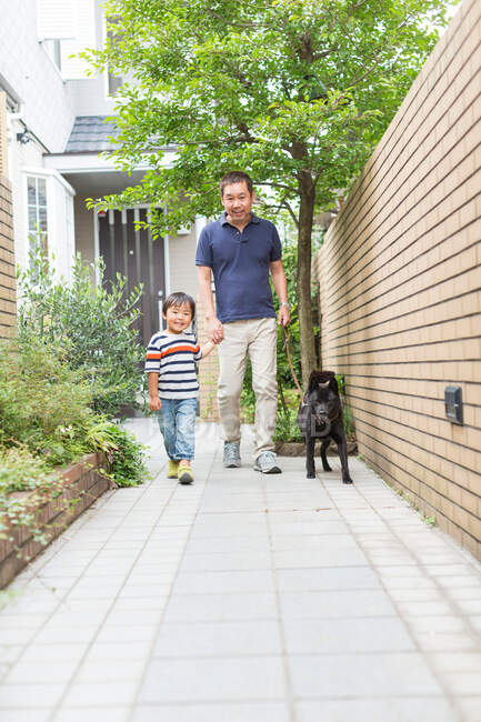 Pai e filho passeando cão no caminho — Fotografia de Stock