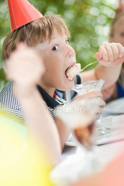 Chico comiendo helado helado en la fiesta - foto de stock