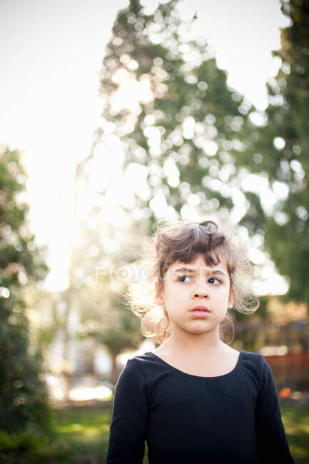 Молодая девушка в саду, смотрит в сторону — стоковое фото