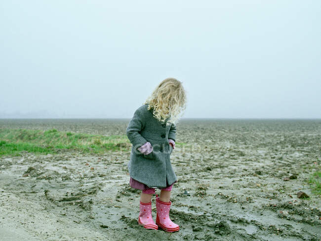 Fille portant des bottes de pluie sur la plage — Photo de stock