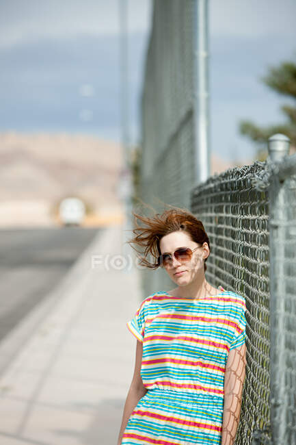 Jeune femme penchée sur une clôture métallique — Photo de stock