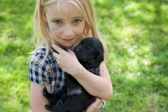 Joven chica abrazar cachorro - foto de stock