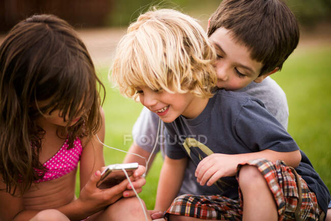 Niños escuchando auriculares al aire libre - foto de stock