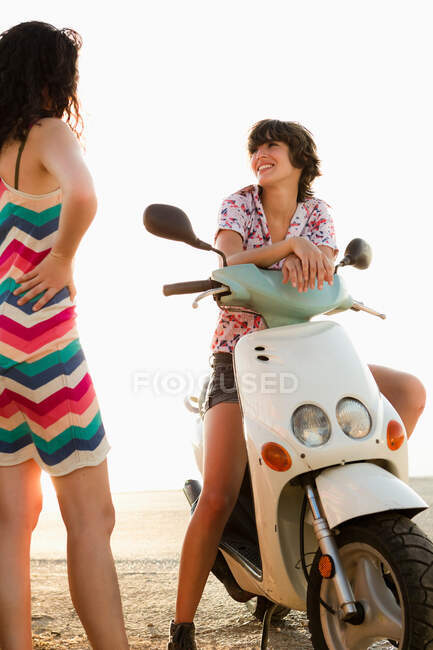 Жінки розмовляють на скутері на пляжі — стокове фото