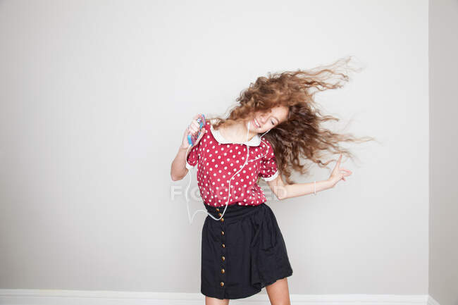Девушка в наушниках, танцует и держит mp3 плеер — стоковое фото
