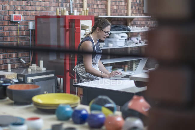 Cape Town, South Africa, young female on laptop in ceramic workshop — Stock Photo