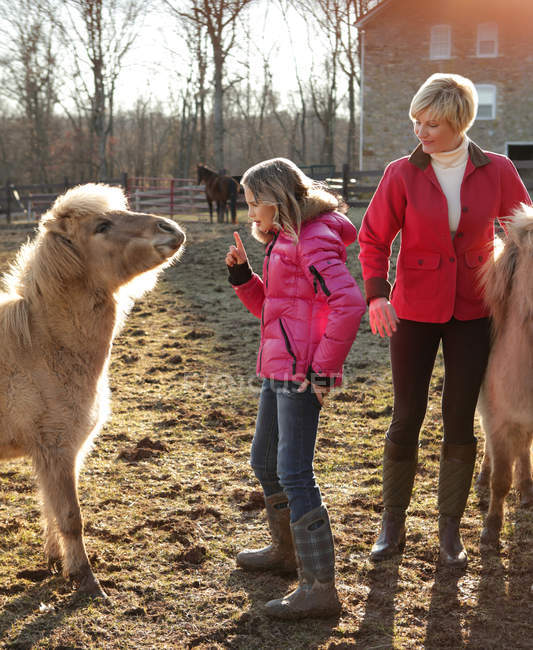 Mother and daughter outdoors, daughter giving instructions to pony — Stock Photo