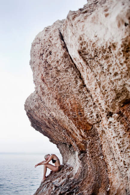 Mulher sentada nas rochas em falésias — Fotografia de Stock