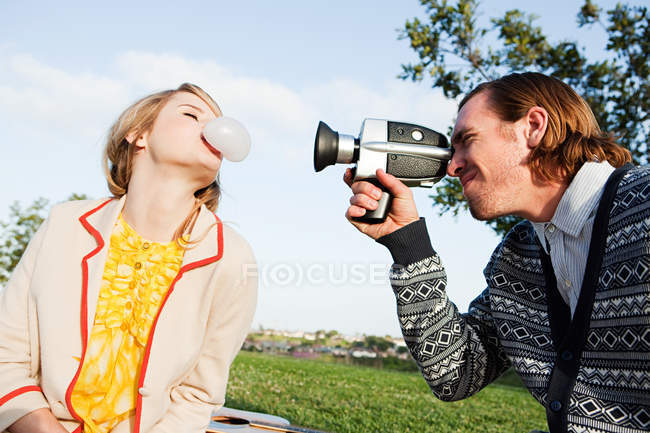 Man filming girlfriend blowing bubble gum — Stock Photo