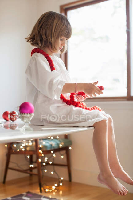 Девушка на столе играет с рождественскими украшениями — стоковое фото