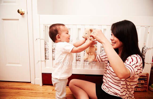 Madre jugando con bebé niño con juguete suave - foto de stock