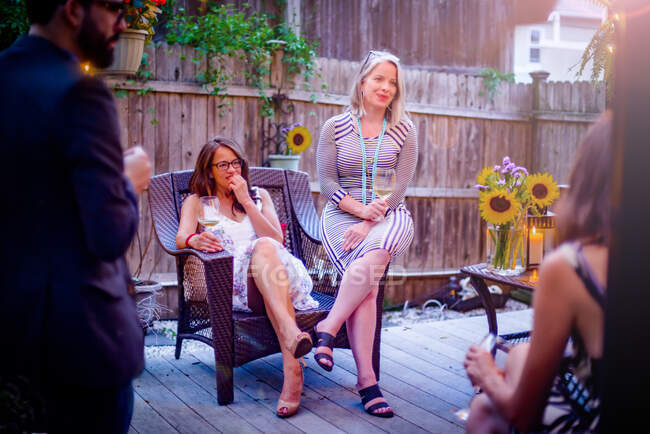 Группа людей на садовой вечеринке, сидящих на палубе, в разговоре — стоковое фото