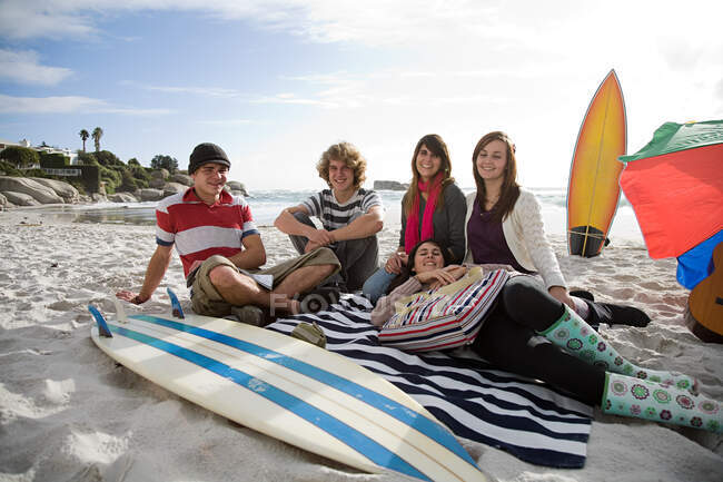 Amigos en la playa con tabla de surf - foto de stock