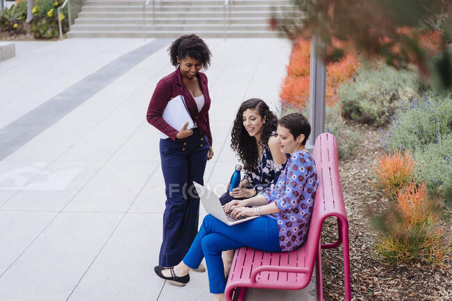 Trois femmes à l'extérieur, regardant un ordinateur portable — Photo de stock