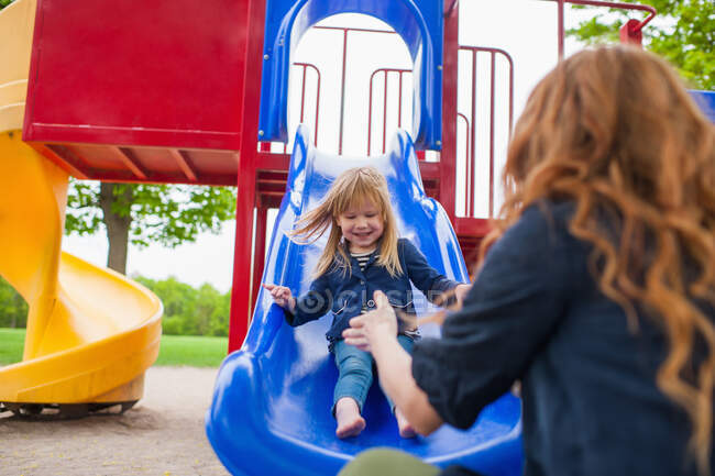Mother catching daughter at the bottom of slide — Stock Photo